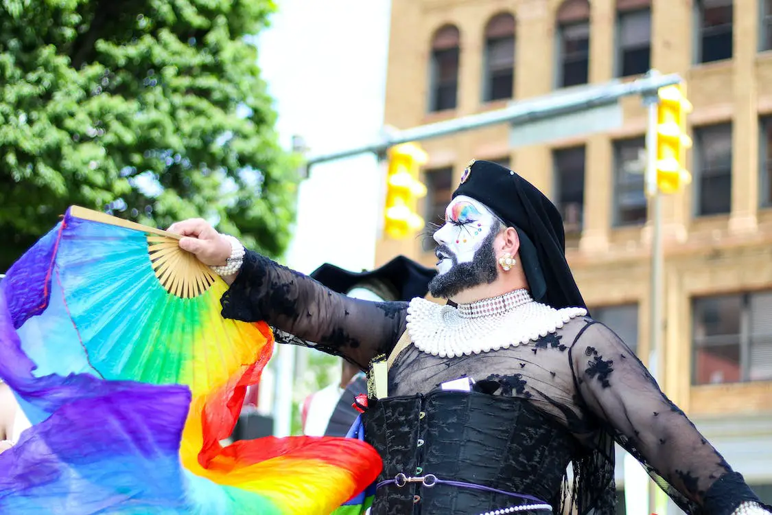 A drag queen holding a rainbow flag during a Pride parade.