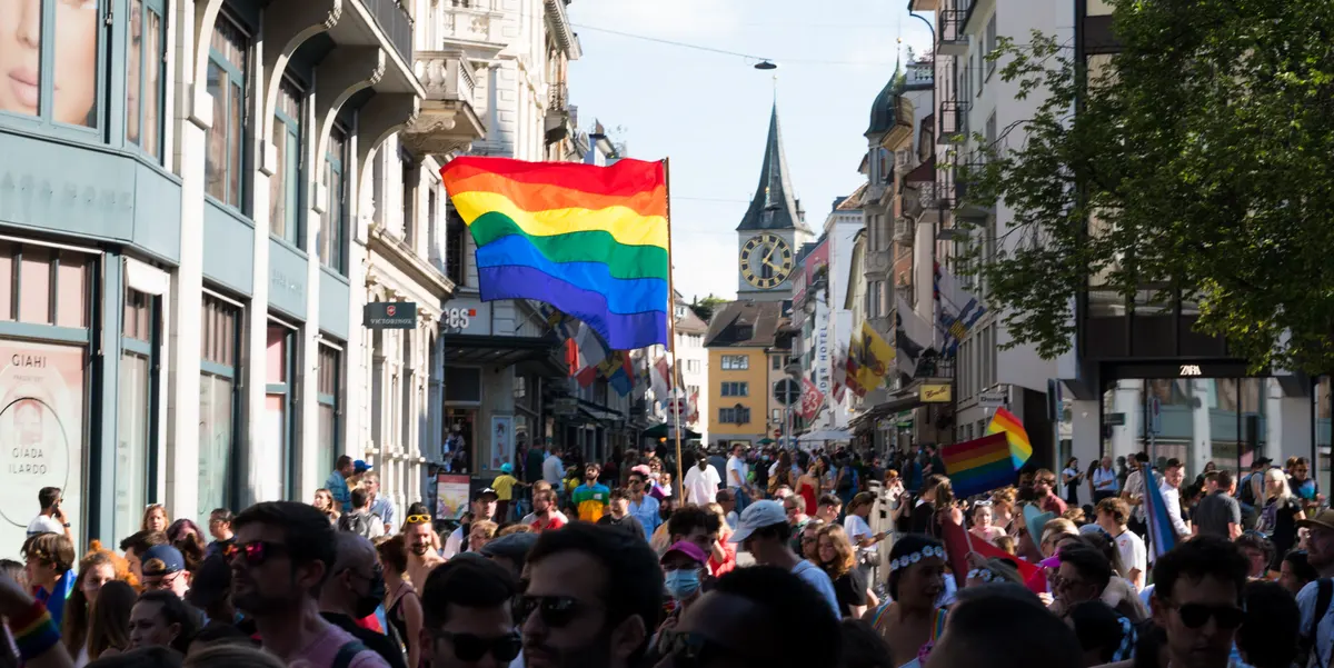 Rainbow flag and people walking during Pride Zurich.