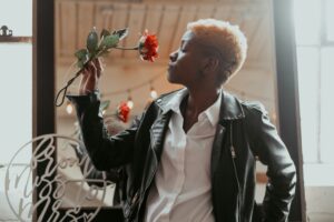 A tomboy wearing a leather jacket and holding a flower.