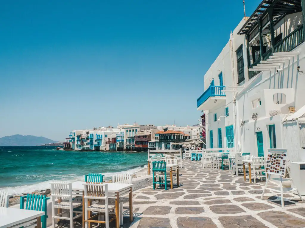A street by the beach in Mykonos with white houses.