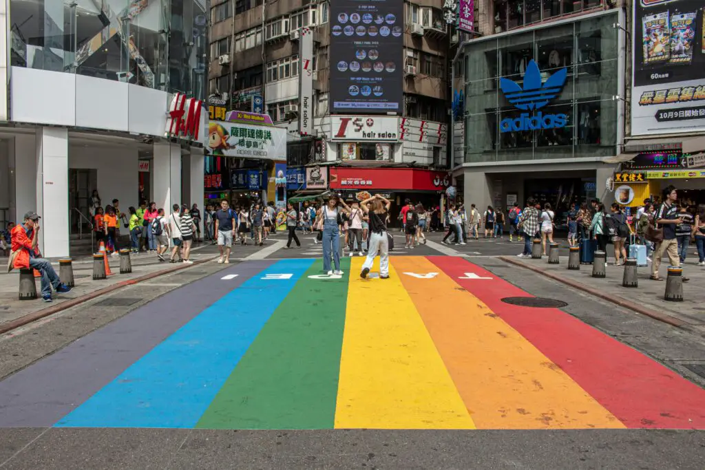 Two People standing on a rainbow flag on one of Taipei streets.